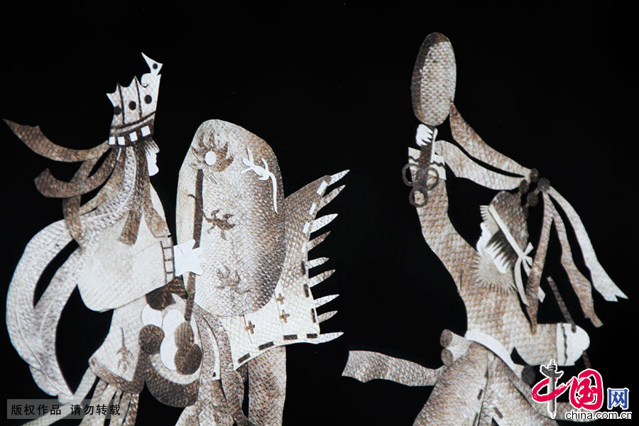  鱼皮画是赫哲族传统的艺术品种。通过对鱼皮的粘贴和镂刻，以独特的形式，从不同角度表现了赫哲族人民的聪明才智和审美的群体意识。图为描绘萨满舞鱼的鱼皮画。中国网图片库 韩加君/摄