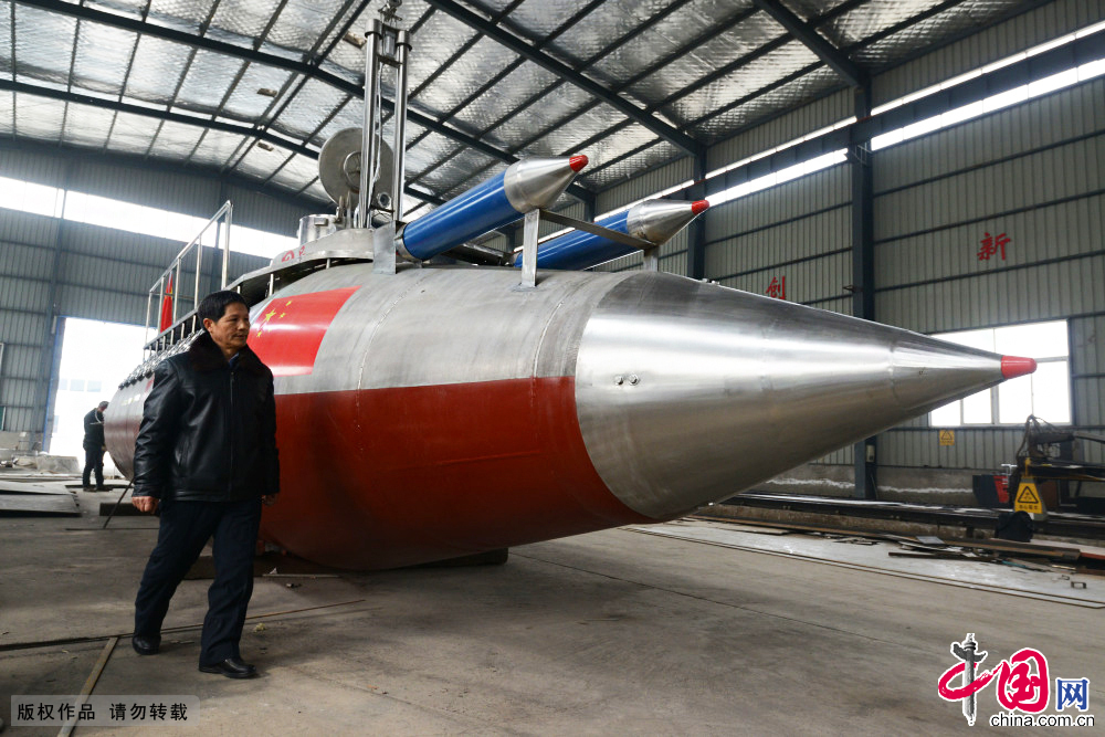 2014年12月20日，在安徽阜阳市一集团的金工车间，张俊林站在“神龙三号”潜艇前。 中国网图片库安新摄影