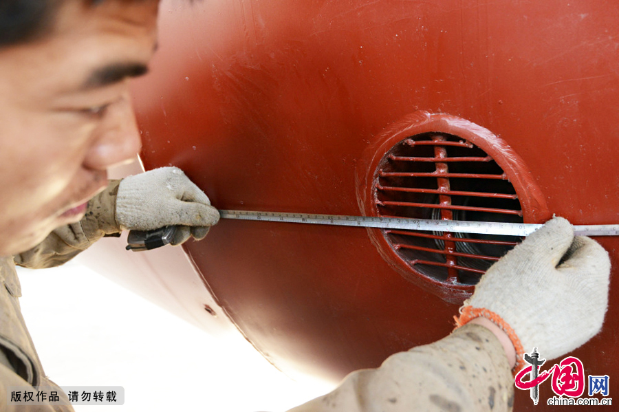  2014年12月21日，在安徽阜阳市一集团的金工车间，技术人员在测量潜艇底部的进出水口。这样的口在潜艇底部附近前后左右有四个。中国网图片库安新摄影