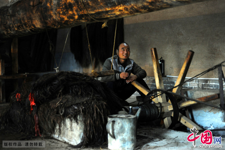 2014年12月20日，老油坊工人高飞在操纵手工榨油工具。