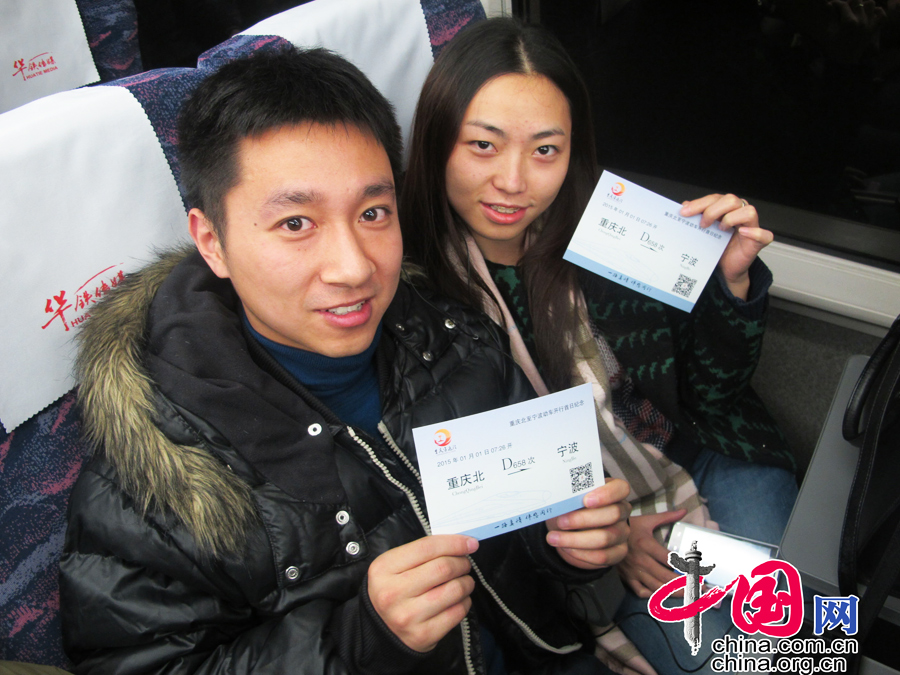乘务员向旅客赠送首发纪念明信片，旅客留影纪念。