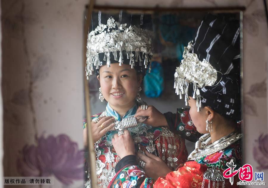 新娘请来十余个伴娘，她们也满戴银饰，身穿盛装，对镜精心打扮。中国网图片库 尹忠/摄 