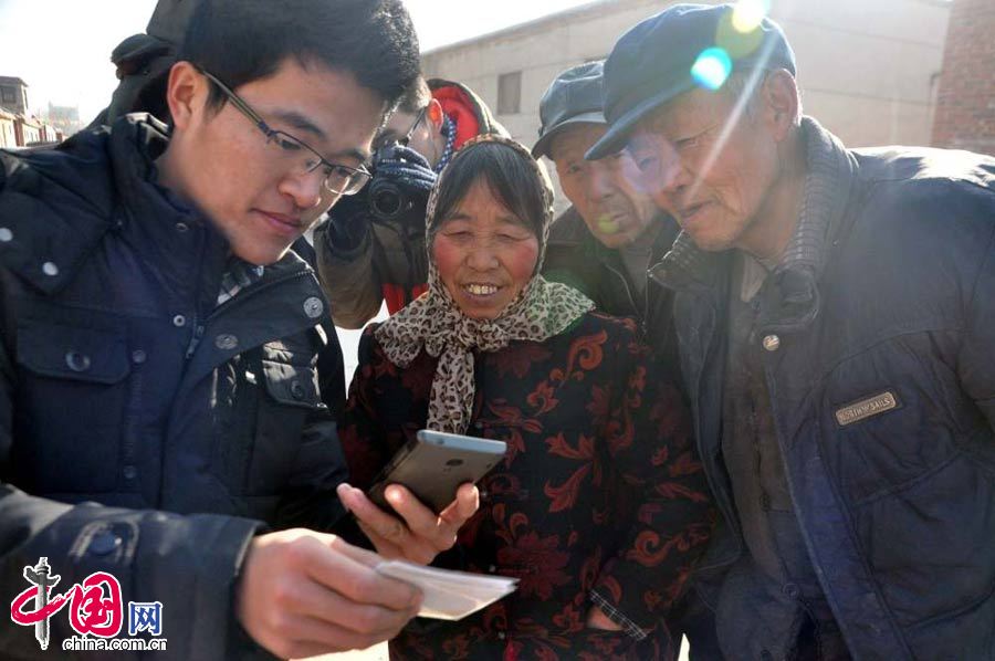 1月17日，在山东省聊城市马官屯村，大学生张金微（左）在给村民用手机演示扫描二维码个人信息。 中国网图片库赵玉国摄影