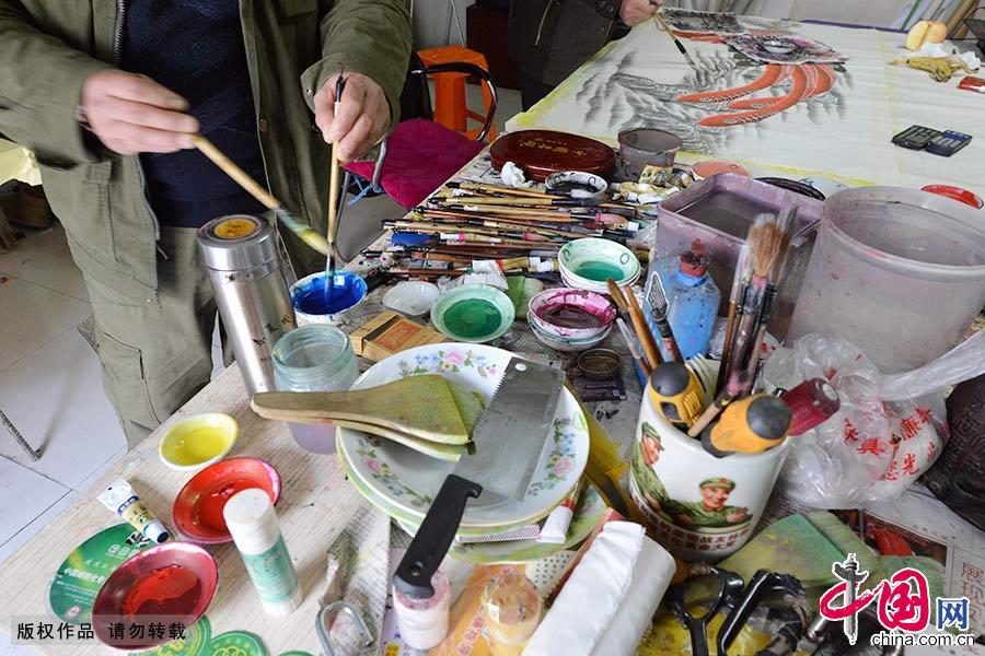 一凤阳凤画艺人在调配颜料，画桌上各种作画工具玲琅满目。中国网图片库 高建业/摄