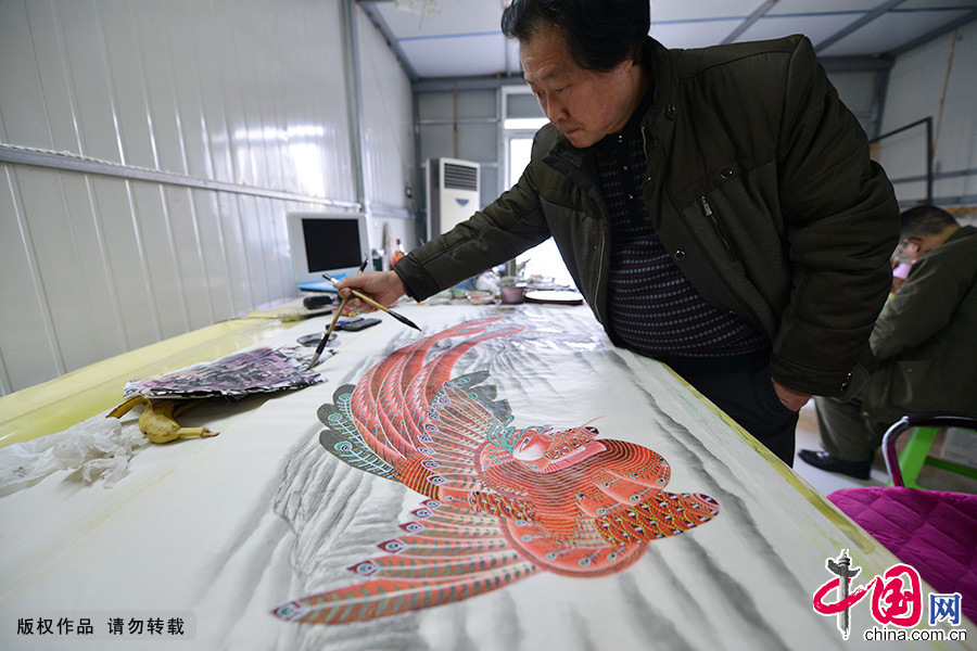 凤画艺人刘耘岗在绘制凤画。和可以印刷的年画不同，凤画需画师纯手工一笔一划绘制，一幅画作少则一周，有的甚至需要用上月余的时间。中国网图片库 高建业/摄