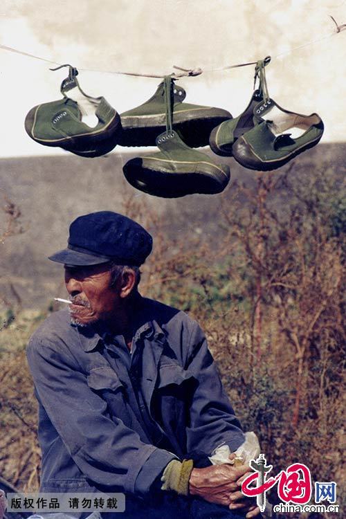 1986年，山东青岛，一位老人在集市上卖胶鞋。在当时，这种“解放鞋”颇为流行。赵国富 摄 