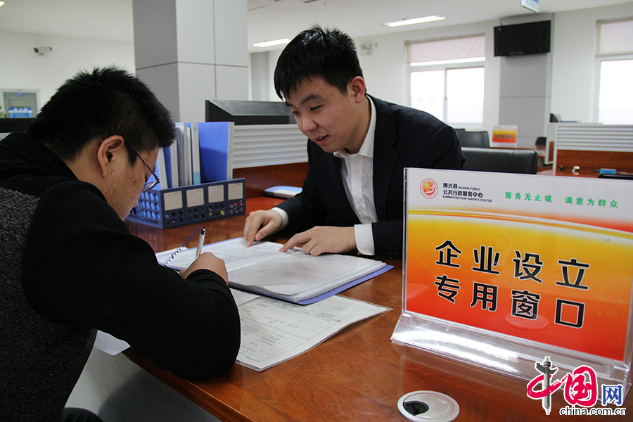 专用窗口工作人员正在细心指导办事群众填写企业设立申请的相关材料。