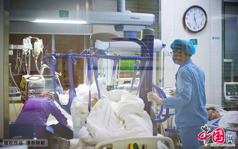  2015年2月7日，鄭州，夜裏11點半，護士為病人例行檢查發現有患者出現發熱症狀，在另一名男護士的配合下，在病人的病床上鋪上醫用冰毯，輔助降溫。 圖片來源：CFP