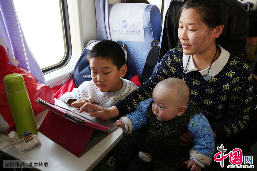 2月5日，趙子云懷抱6個月的寶寶與大兒子石聖榮在K8305次列車玩平板電腦。中國網圖片庫 郭志華/攝