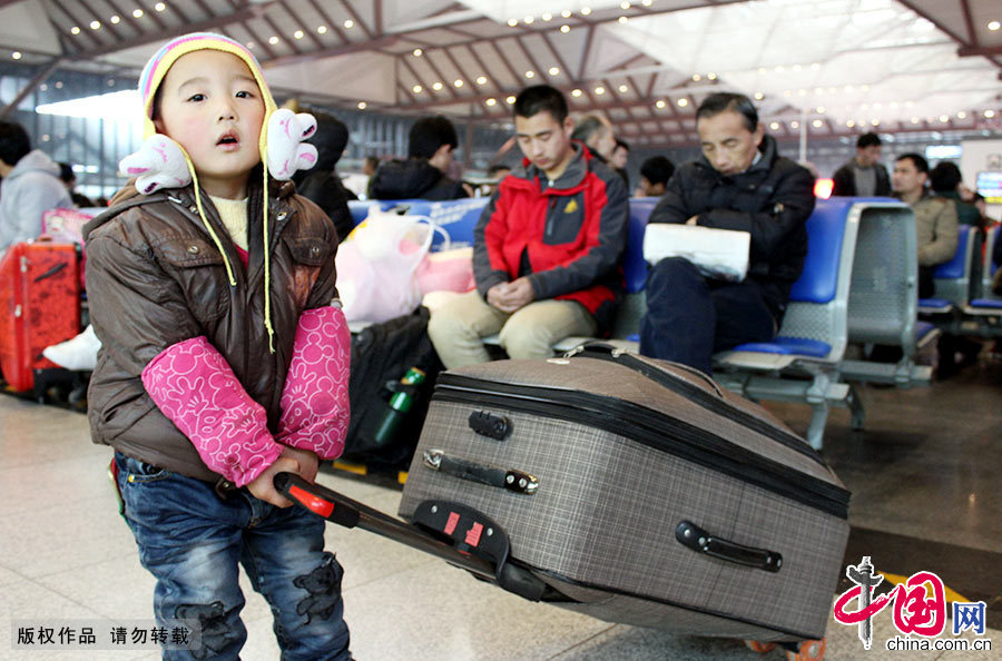  2月4日，一名小朋友在江苏苏州火车站拉着行李跟随父母前来乘车返乡。江苏苏州是劳务输入较多的城市，有着数百万外来务工人员，随迁子女为数众多。中国网图片库 郭志华/摄 