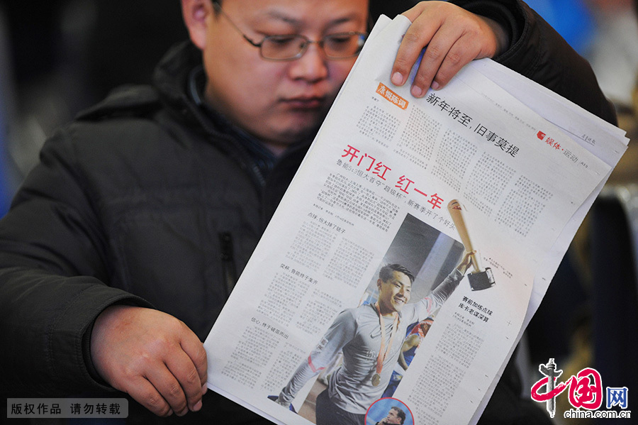 2015年2月15日，“开门红 红一年”，一名在青岛火车站候车室等车的旅客看着报纸打发时间。中国网图片库 王海滨/摄
