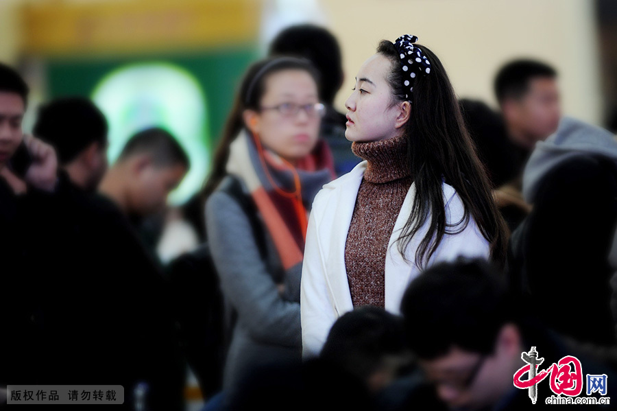 2015年2月15日，一名在青岛火车站准备乘车的女孩在茫茫人海中寻找同伴。中国网图片库 王海滨/摄