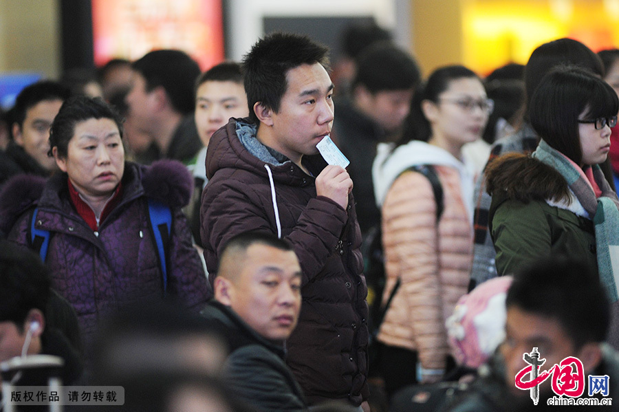 2015年2月15日，一名嘴衔车票的旅客准备乘车，这一举动代表了多数返乡者的迫切心情。中国网图片库 王海滨/摄　