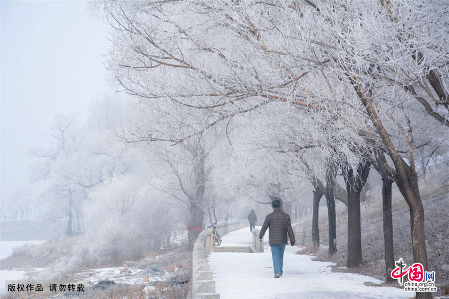 2015年3月3日，吉林省吉林市，人們在吉林市松花江畔美麗的春日霧凇前行走。中國網圖片庫 王明銘/攝