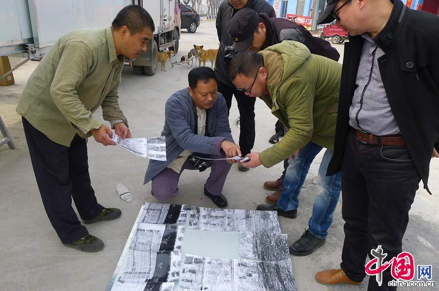 3月7日，在河南省焦作市，一台總長13米的超級照相機亮相街頭。圖為李宗澤（左一）介紹他拍的測試樣片。中國網圖片庫 龍邦/攝