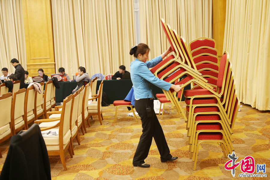 会议中临时增加的椅子要放回库房，孙娜吃力地搬起四把椅子。 中国网记者 董宁摄影