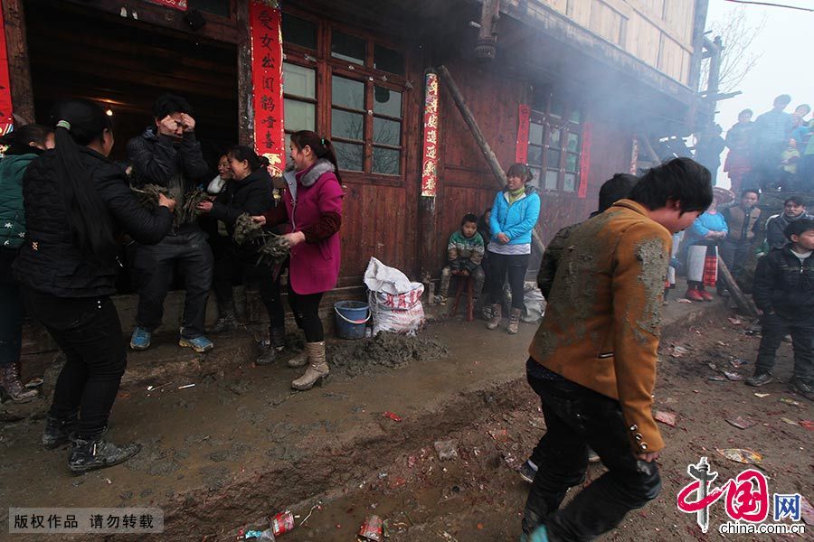  喜酒喝过四轮，鞭炮一响，媒人公们往门外冲去。早在门边守候的女方姑娘们用稀泥巴朝媒人公身上、背上狠狠的“打泥巴”，媒人公个个兴高采烈。中国网图片库 曾勇/摄 