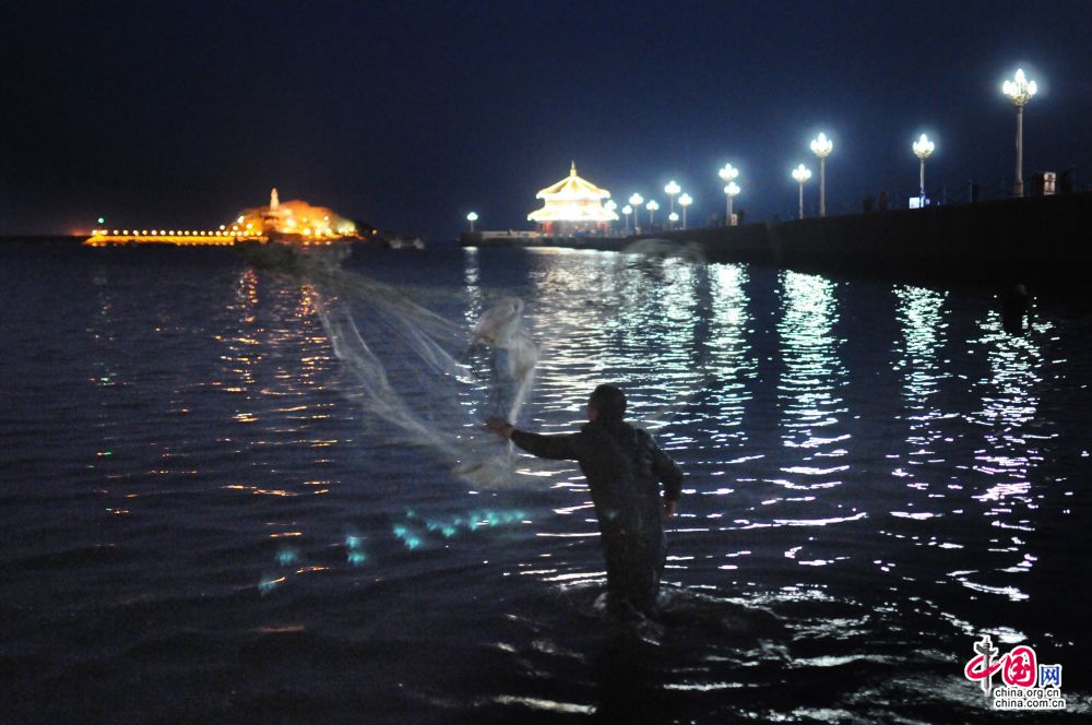 　　2015年3月26日，青島棧橋一側水域，市民趁夜幕漲潮時段撒網捕撈梭魚。中國網圖片庫 王海濱/攝 