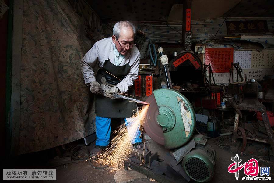 老人用现代砂轮进行铁器的打制。中国网图片库 王振东/摄 