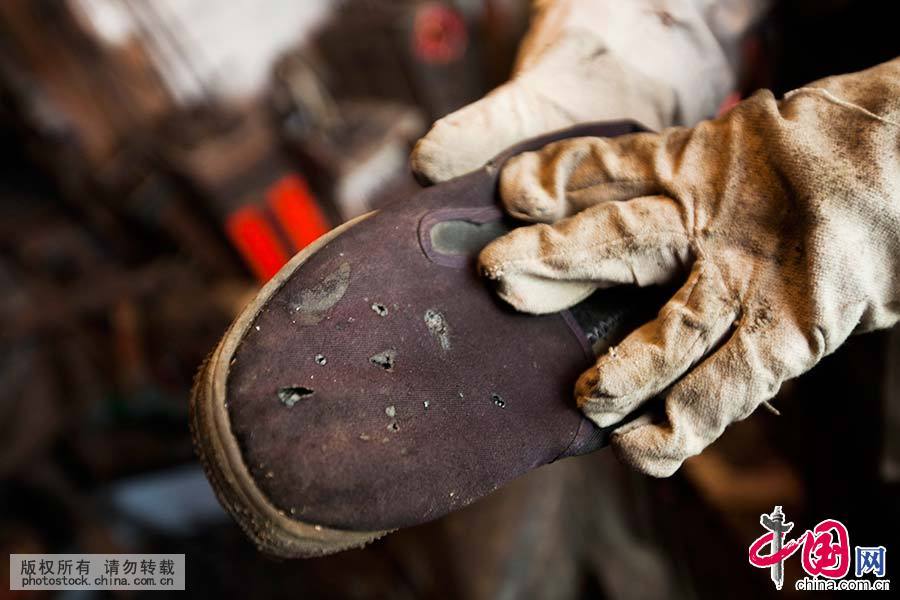 在工作时，老人鞋子也被电焊烧破了。中国网图片库 王振东/摄 