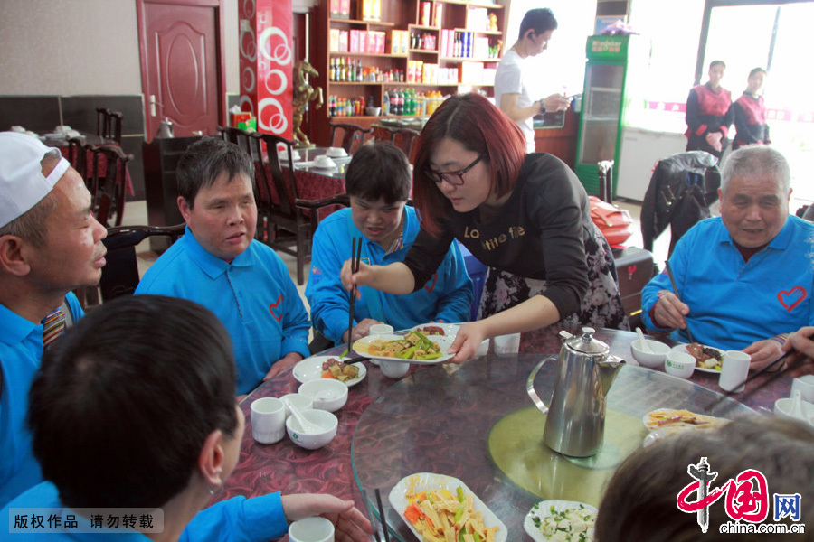 午饭时志愿者为盲人朋友分菜。中国网图片库 冯磊