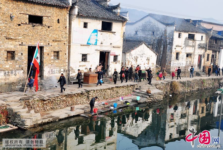 在江西省婺源县秋口镇长径村，艺人举着傩旗经过村庄。中国网图片库 胡敦煌/摄