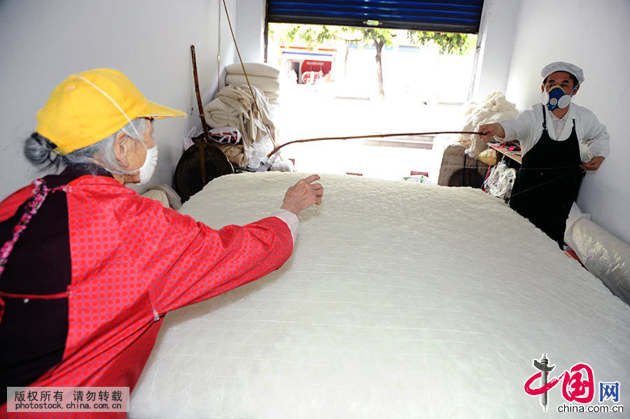 这是王定民在母亲的协助下拉网线，为社区居民加工棉被。中国网图片库 饶国君/摄