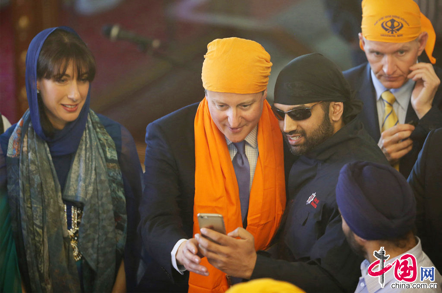  当地时间2015年4月18日，英国格雷夫森德，英国首相卡梅伦携妻子参加锡克教Vaisakhi节日，二人身着锡克教传统服饰，为选举造势。图片来源：CFP