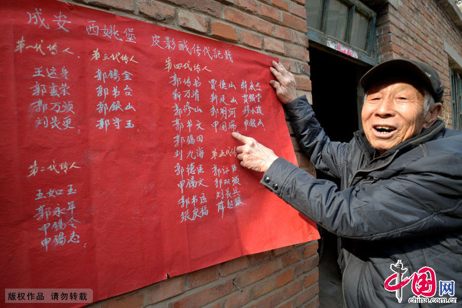 申國瑞正在向我們介紹河北省邯鄲市成安縣西姚堡村皮影戲傳代記載情況。80歲的老人家指著墻頭紅紙上第四代傳人自己名字的位置，頗感自豪。中國網圖片庫 郝群英攝 