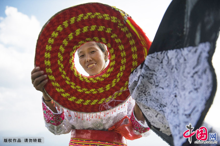  花瑶女性喜头戴宽大的由红、黄色彩带缠成的反斗笠状的圆盘头饰，色彩艳丽，上大下小，可以遮挡阳光。中国网图片库 尹忠摄 