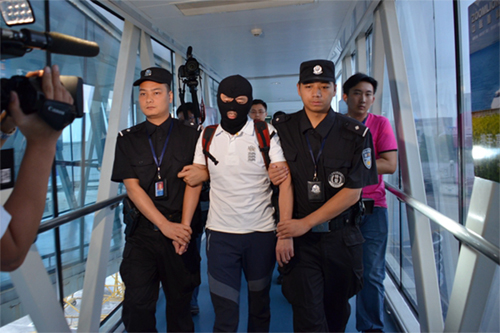 潛逃泰國43天，涉嫌受賄犯罪、掩飾隱瞞犯罪所得的祁某某（中）在民警的押解下走出航班