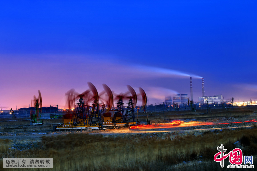 2015年2月19日，大慶油田採油二廠，夜幕中工作的抽油機和遠處的大慶熱電廠。中國網圖片庫 劉國興攝