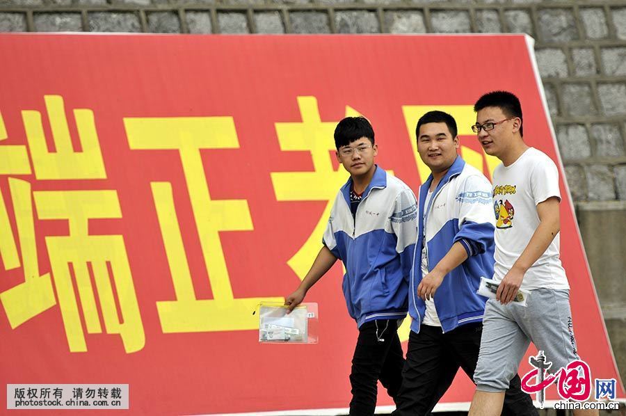 6月7日，在山东郯城一中考点，三名考生从“端正考风”的宣传牌前走过。中国网图片库 房德华 摄