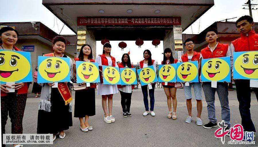 6月7日，在河南省夏邑高级中学考点门口，义工用笑脸牌摆出各种笑脸集合图案，迎接考生入场。中国网图片库 苗育才 摄