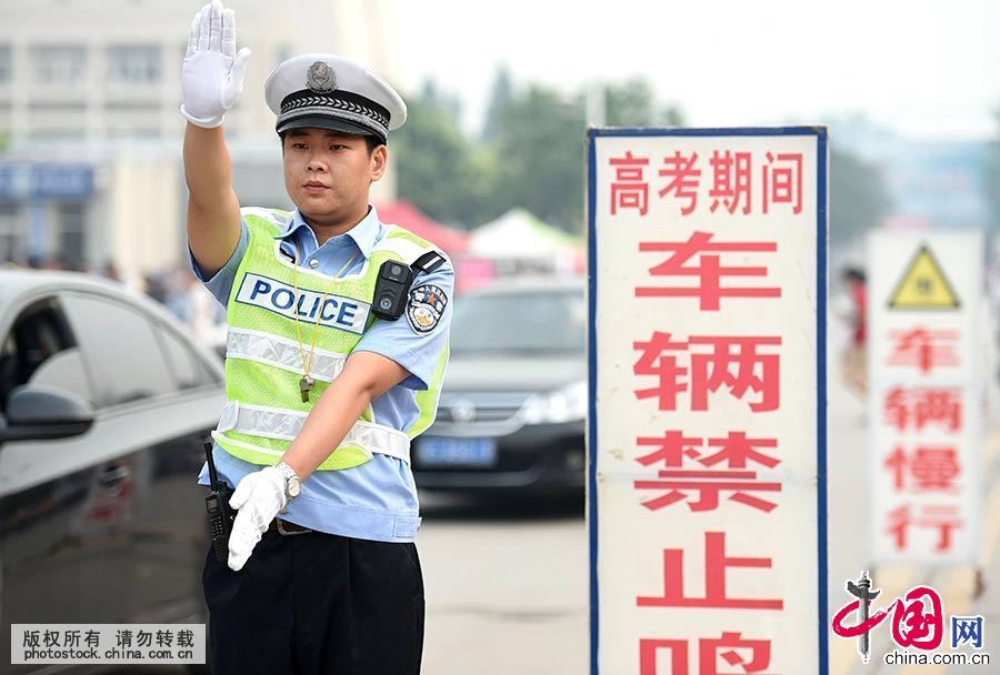 6月7日，一名交警在安徽省亳州一中学考点外设置的禁鸣标志旁执勤。中国网图片库 刘勤利 摄