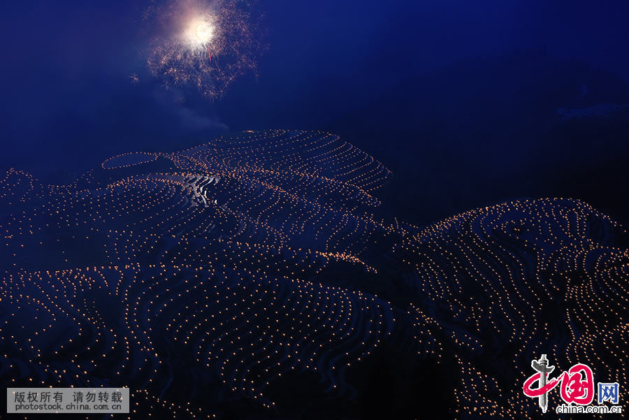  入夜，平安壯寨村民在形如“七星伴月”的梯田上點燃萬支火燭，呈現繁星閃爍的美麗壯錦。同時，燃放煙花，剎時，煙花騰空，五彩繽紛。 中國網圖片庫 肖遠泮 攝