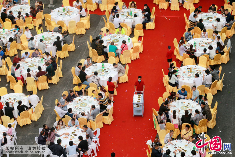 6月9日，贵州安顺千人宴免费吃现场，一名服务员在上菜。中国网图片库 卢维摄