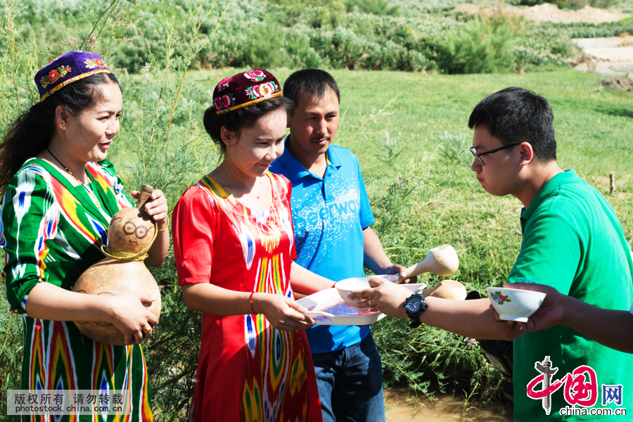  新疆伊吾下马崖苏乃孜节上，当地维吾尔族姑娘给参加清淤的群众送来甘甜的坎儿井水，以示感谢。中国网图片库 孙继虎摄