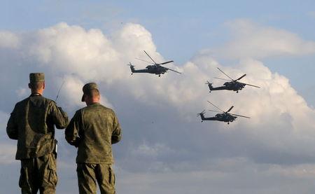 Russian servicemen watch Mi-28 military helicopters of the Berkuti aerobatic team fly during the opening of the Army-2015 international military forum in Kubinka