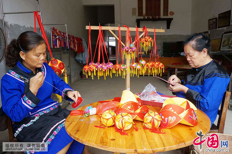 6月21日，在广西靖西县新靖镇旧州街，绣球传承人黄肖琴与儿媳一起绣球瓣。中国网图片库韦万忠 摄 