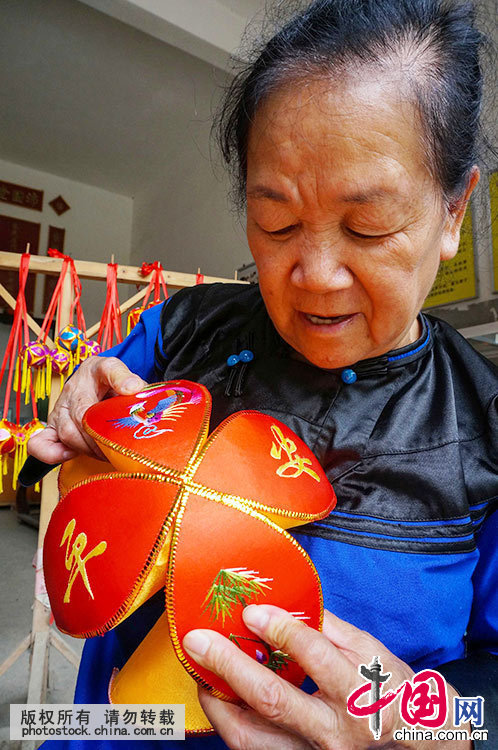 6月21日，在广西靖西县新靖镇旧州街，绣球传承人黄肖琴在对准合拢球瓣。中国网图片库 韦万忠 摄