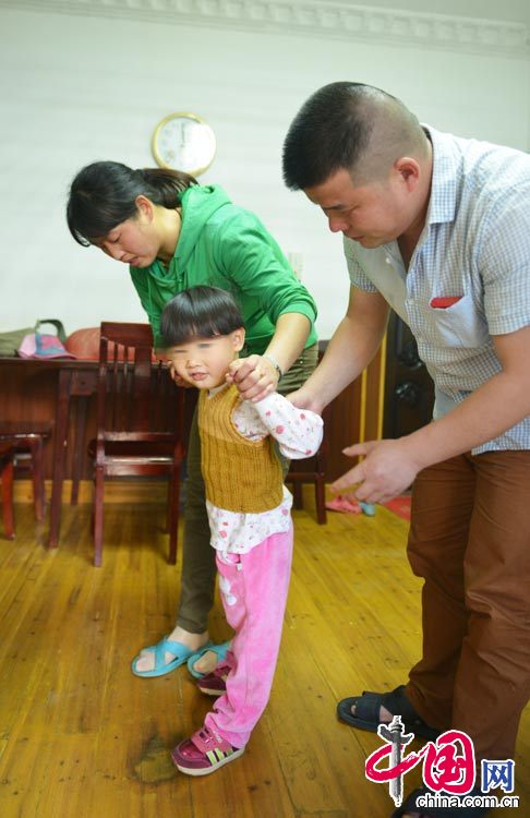圖為今年4月份拍攝，小雅婷在去上海治療之前，徐建華夫婦扶著她走路，由於逆生長，小雅婷4歲了仍不能走路。中國網圖片庫