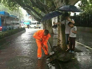 南京:过路父子雨天为疏导阴沟工人撑伞