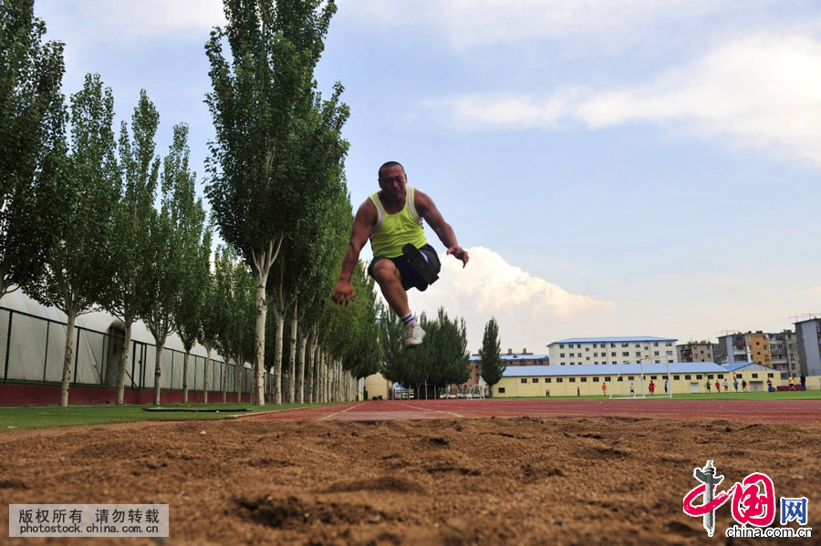  6月28日，在内蒙古体育职业学院操场，铁钢正在进行跳远训练。铁钢是学校里唯一的残疾运动员，他在训练场上的每个举动都能给人们带来震撼。不少学生看见他刻苦训练的身影，把他视为榜样。中国网图片库 王伟摄