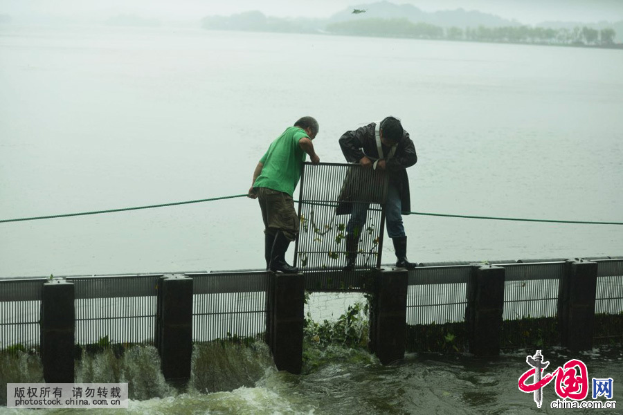  2015年7月11日，浙江省杭州市，杭州西湖水域管理處的工作人員在聖塘閘人工啟動西湖泄洪。當日，受到超強颱風“燦鴻”週邊雲係的影響，杭州風雨是明顯加大，西湖遊客也是顯著減少。中國網圖片庫 龍巍攝