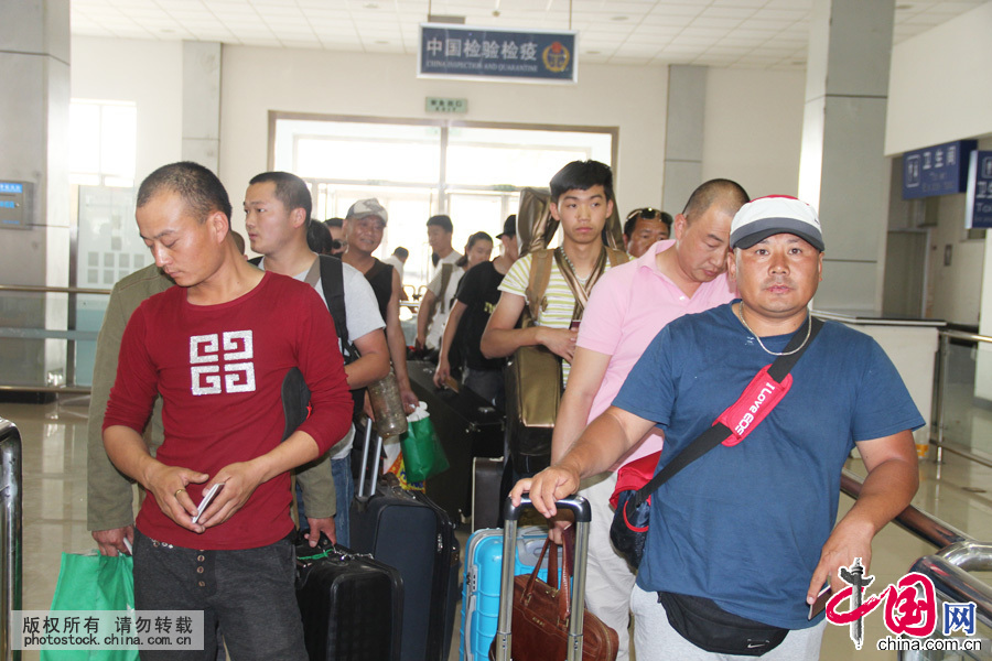 2015年7月14日，工人們有序排隊等待辦理入境通關手續。中國網圖片庫 郭鵬傑攝