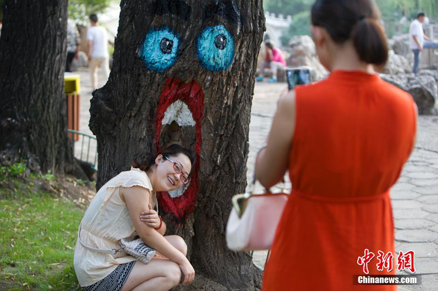 来此游玩的民众被树干上的"树洞画"所吸引,纷纷围观拍照.