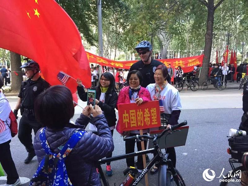 當地兩位華人拿著印有“中國的希望”的牌子前合影 周竹攝