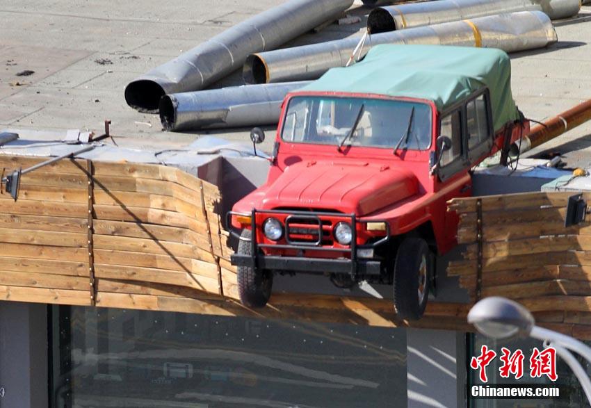 10月14日消息，吉林省吉林市一建筑顶部，近来出现一辆半悬空中的吉普车，引来路人关注