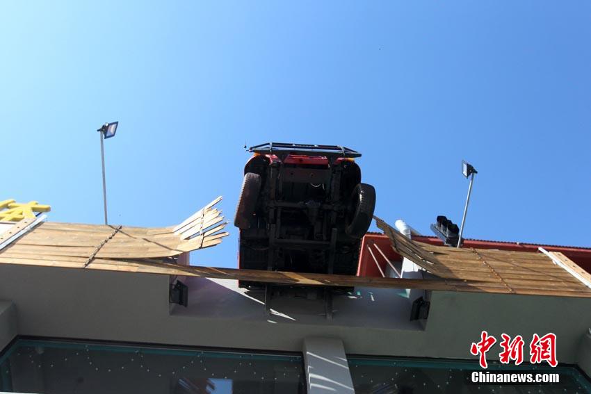 10月14日消息，吉林省吉林市一建筑顶部，近来出现一辆半悬空中的吉普车，引来路人关注